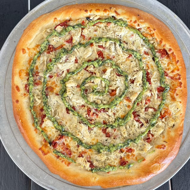 Oil base, cheese, sundried tomatoes, seasoned chicken, pesto swirl on top.