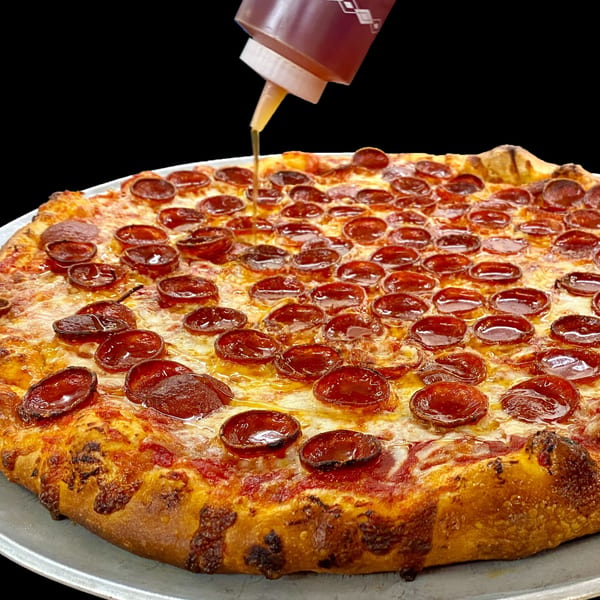 A pepperoni pizza from Sally O'Neal's Pizza Hotline being drizzled with honey from a squeeze bottle.