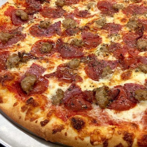 Close-up of a Sally O'Neal's pepperoni and sausage pizza with melted cheese and a crispy crust.